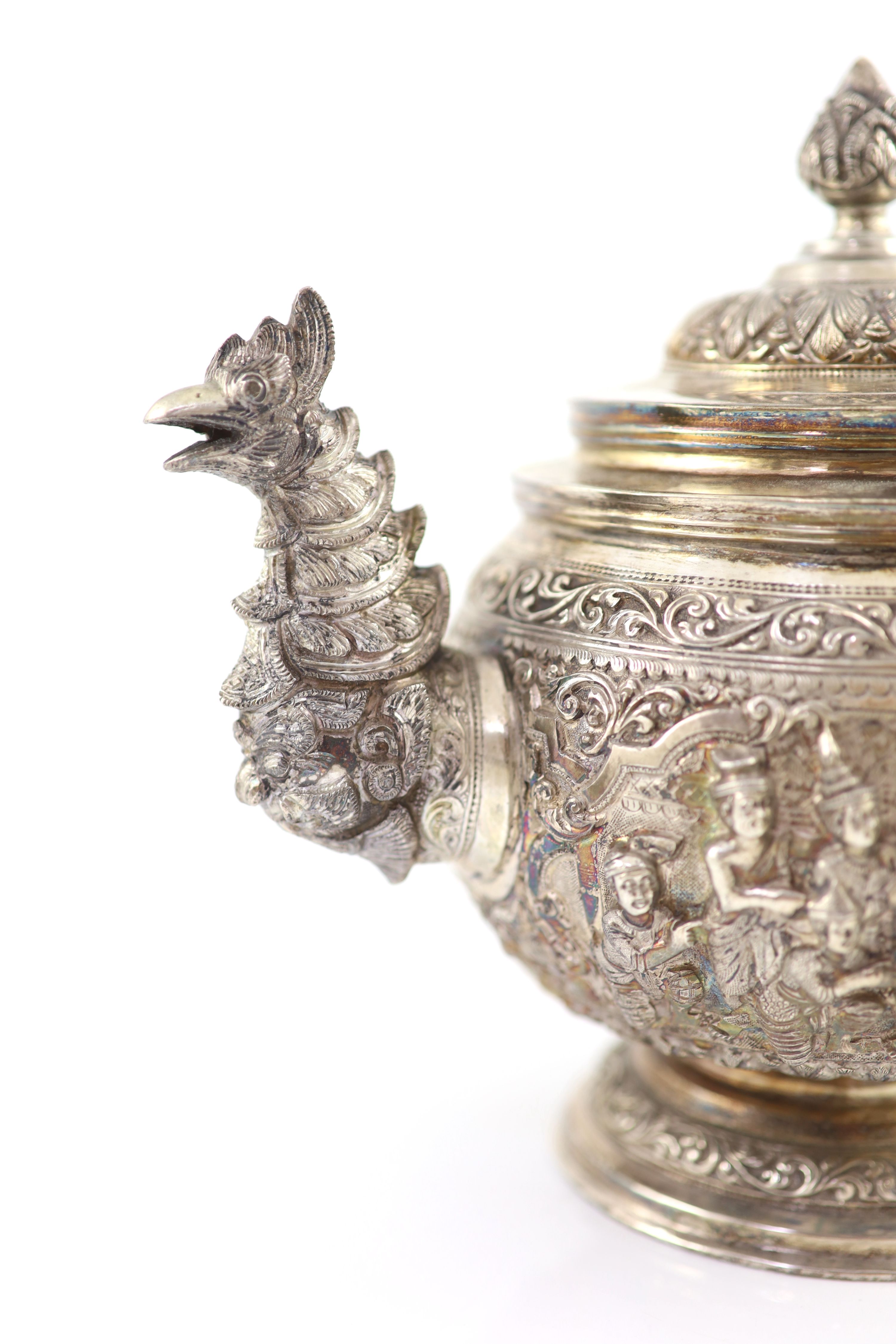 An impressive Burmese Sterling silver (950) three-piece tea service, with tray, cast with figures, teapot with cockerel spout and figural handle